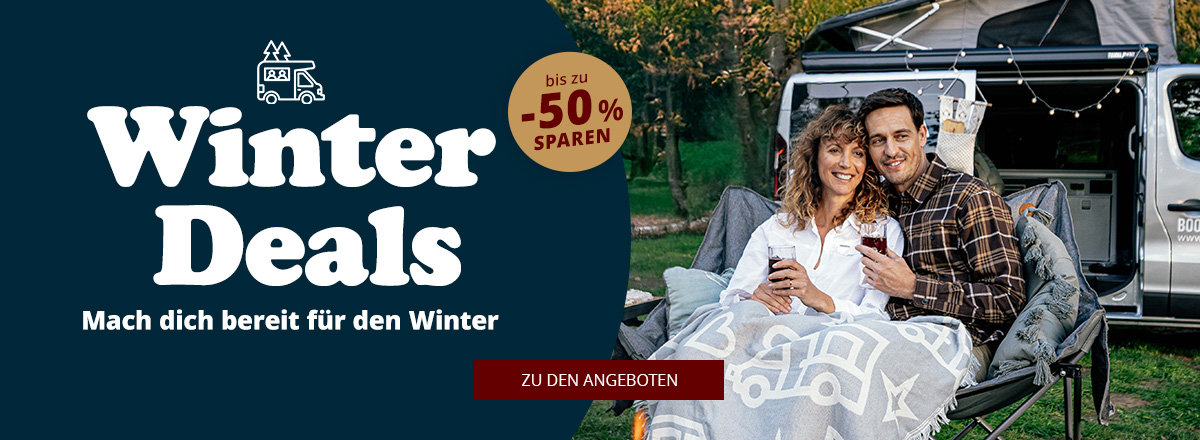 Zwei Personen sitzen im offenen Heck eines Wohnmobils, unter einer Decke mit weißen Camper-Silhouetten; links dunkler Hintergrund mit großem Text 'Winter Deals', kleinem Text 'Mach dich bereit für den Winter', rundem Badge 'bis zu 52% sparen' und rot