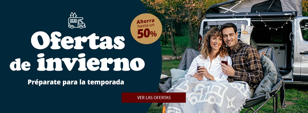Dos personas están sentadas en la parte trasera abierta de una autocaravana, bajo una manta con siluetas de autocaravanas blancas; a la izquierda fondo oscuro con el texto grande 'Winter Deals', texto más pequeño 'Mach dich bereit für den Winter', distintivo redondo 'bis zu 52% sparen' y botón rojo 'Zu den Angeboten'. Césped y árboles de fondo