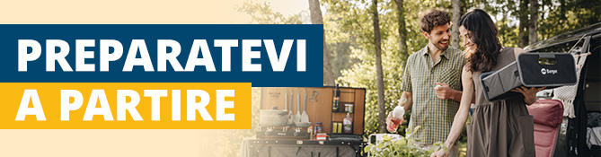 Due persone accanto a un'auto con il bagagliaio aperto; a sinistra uno striscione con 'REISE-VORBEREITUNG'; alberi sullo sfondo