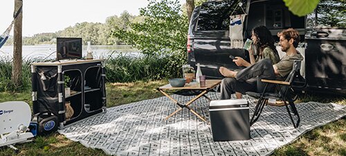 Paar isst Wassermelone vor einem Campingbus in der Natur