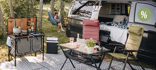 Fünf Personen sitzen abends im Freien an einem Campingtisch vor einem Wohnmobil