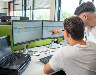 Person zeigt auf Diagramme und Grafiken auf einem Bildschirm