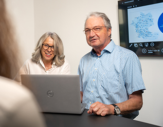 Person zeigt auf Diagramme und Grafiken auf einem Bildschirm