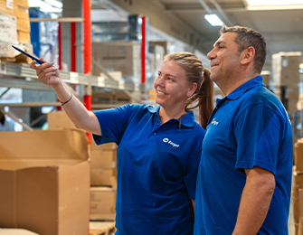 Blick in einen Lagergang mit hohen Regalen und gestapelten Kartons