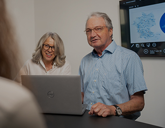 Person zeigt auf Diagramme und Grafiken auf einem Bildschirm