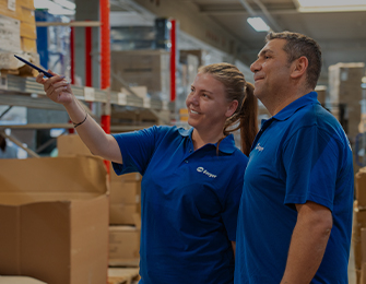 Blick in einen Lagergang mit hohen Regalen und gestapelten Kartons