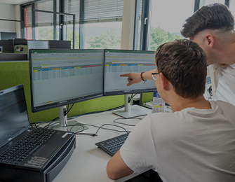 Person zeigt auf Diagramme und Grafiken auf einem Bildschirm