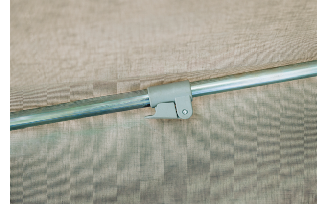 Horizontale silberne Metallstange mit grauem Befestigungsclip vor beigefarbenem, strukturiertem Stoff