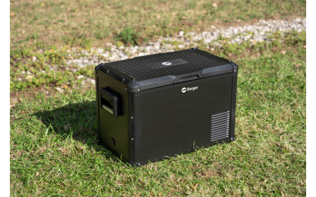 Caisse rectangulaire noire avec poignées et grilles d'aération sur de l'herbe