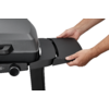 Two hands hold a black side panel next to a gray gas grill on a white background