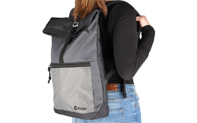 Person von hinten mit schwarzem Rucksack aus Stoff und Netzmaterial, trägt schwarze Kleidung und blaue Jeans