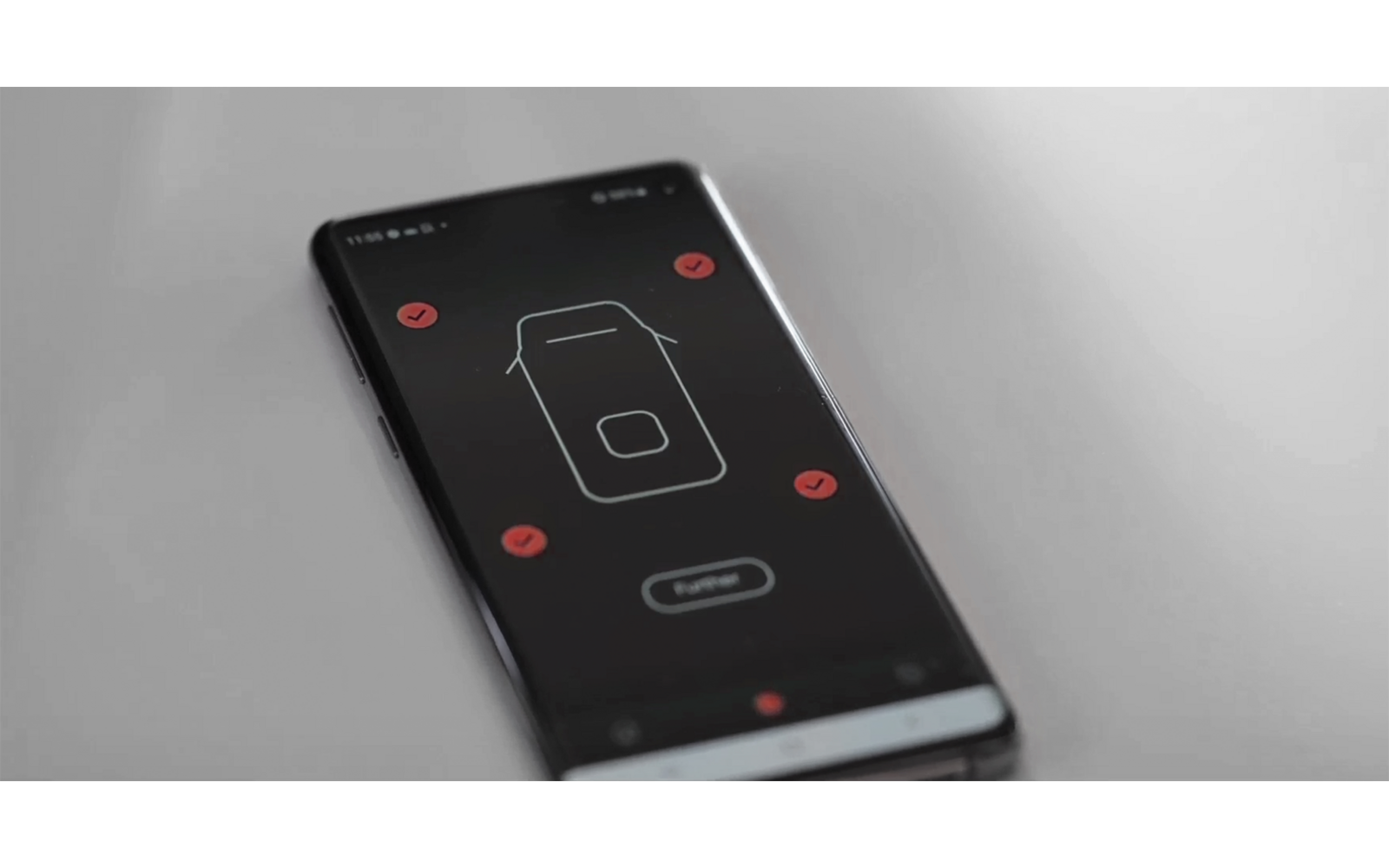 Smartphone noir sur une surface claire, écran affichant une interface sombre avec un contour rectangulaire blanc, un petit carré intérieur, plusieurs cercles rouges et un bouton ovale en dessous