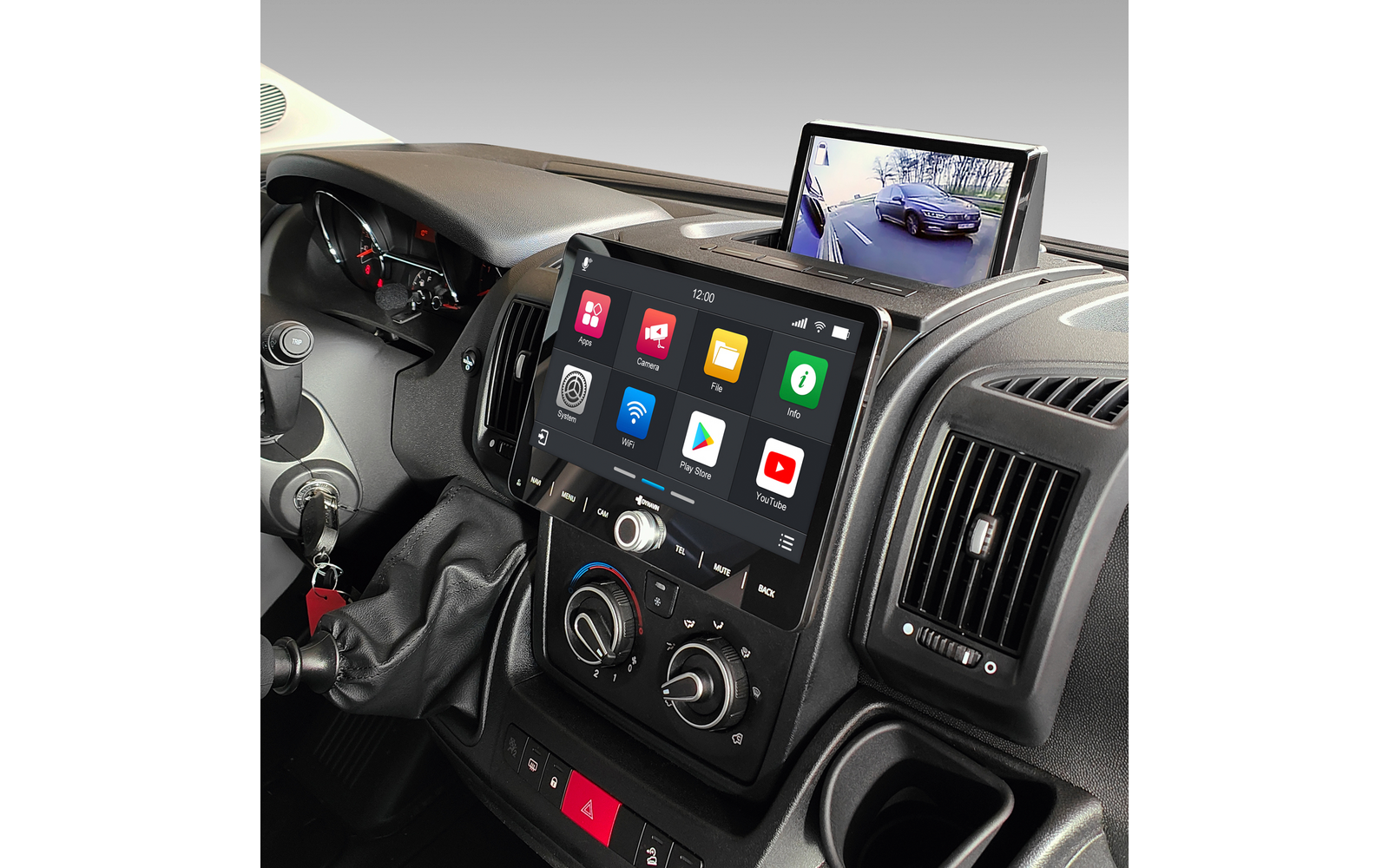 Fahrzeug-Innenraum mit Mittelkonsole, großem Touchscreen mit App-Symbolen, aufgeklapptem Monitor mit Kamerabild eines Autos und einer Straße, Schalthebel, Schlüssel im Zündschloss und Luftdüsen