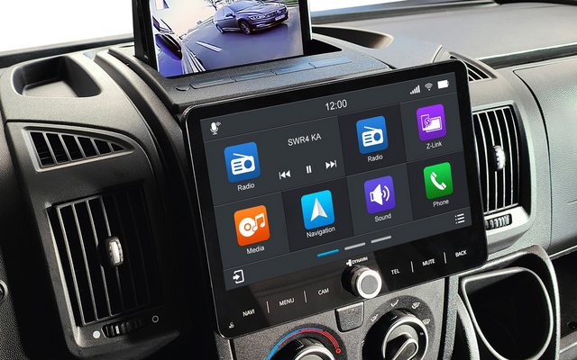 Mittelkonsole eines Fahrzeugs mit großem Touchscreen mit App-Symbolen, klappbarem Monitor oben, der ein Bild eines geparkten Autos und der Umgebung zeigt, Lüftungsdüsen und Drehreglern für die Klimasteuerung