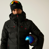 Person mit schwarzer Winterjacke, Kapuze und Skibrille auf dem Kopf, hält einen Skihelm unter dem Arm