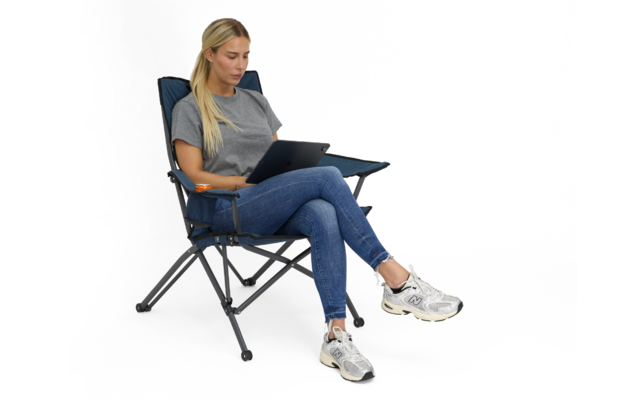 Person mit langen blonden Haaren sitzt in klappbarem Campingstuhl und nutzt einen Laptop auf dem Schoß; graues T‑Shirt, blaue Jeans, weiße Sneakers; weißer Hintergrund