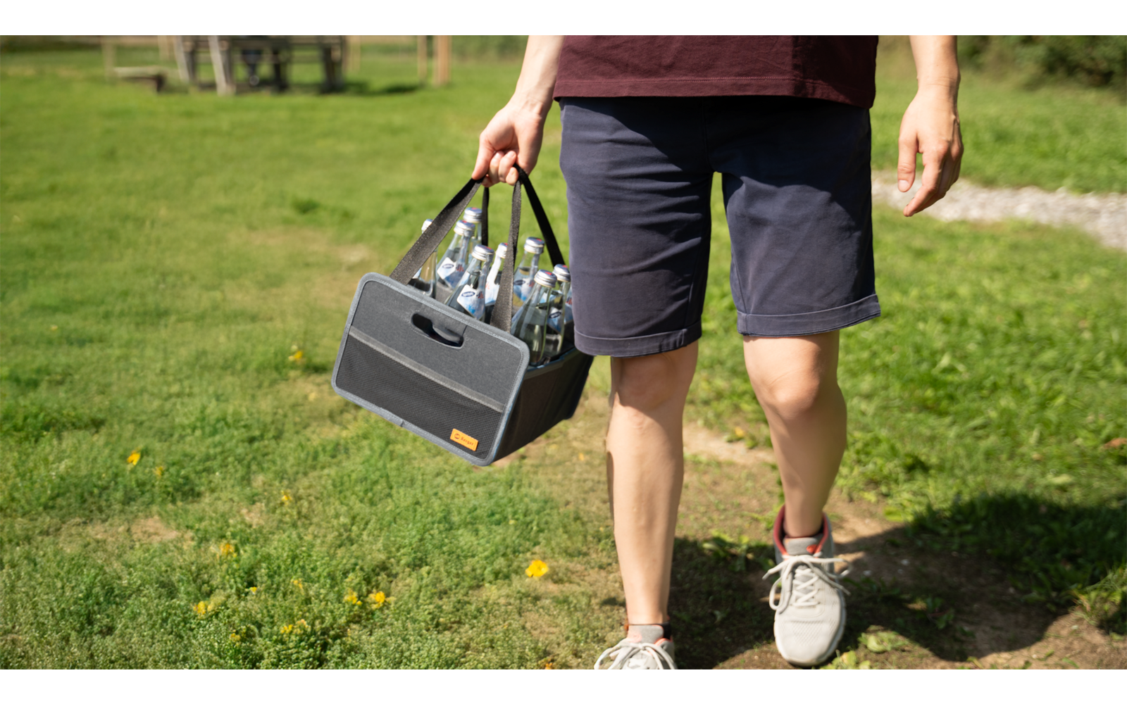 Personne portant un petit haut-parleur à la main, marchant sur un chemin dans un espace vert