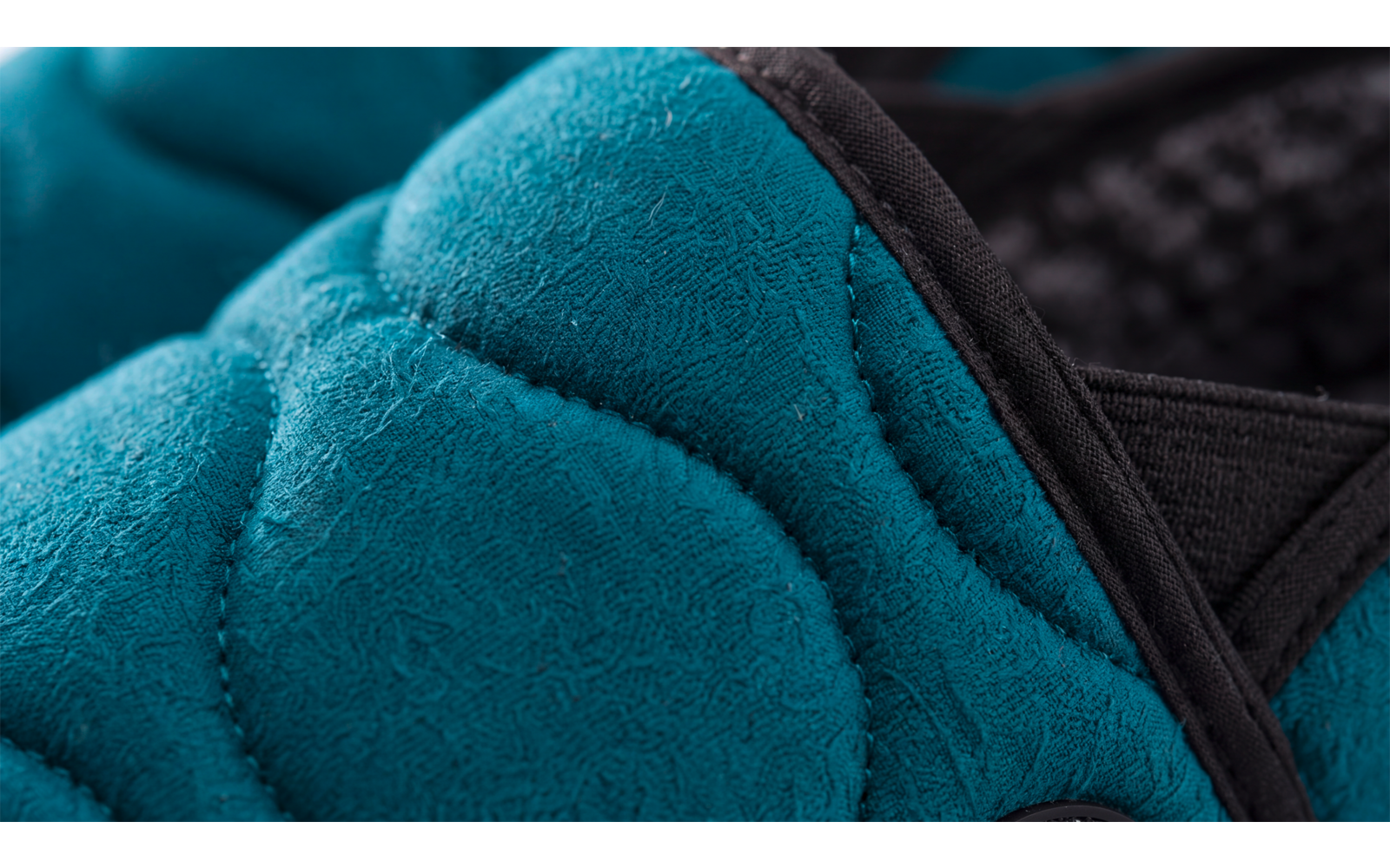 Gros plan d'un rembourrage matelassé turquoise avec bordure noire et tissu en maille noir