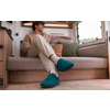 Personne assise sur la banquette d’un camping-car, jambes croisées, porte des chaussons bleu-vert