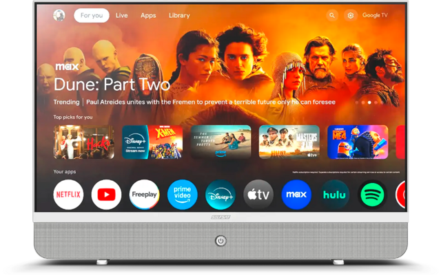 Televisore piatto su piedistallo che mostra la schermata principale di streaming: banner arancione con la scritta "Dune: Part Two" e ritratti dei personaggi; sotto una fila di icone di app come Netflix, YouTube, Prime Video, Disney+, Apple TV, Max, Hulu, Spotify