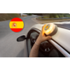Hand mit Armband hält eine gelbe runde Leuchte auf dem Autodach; Blick aus dem Innenraum über Lenkrad und Außenspiegel auf eine kurvige Straße mit Leitplanke; oben links ein kreisförmiges Symbol mit spanischer Flagge