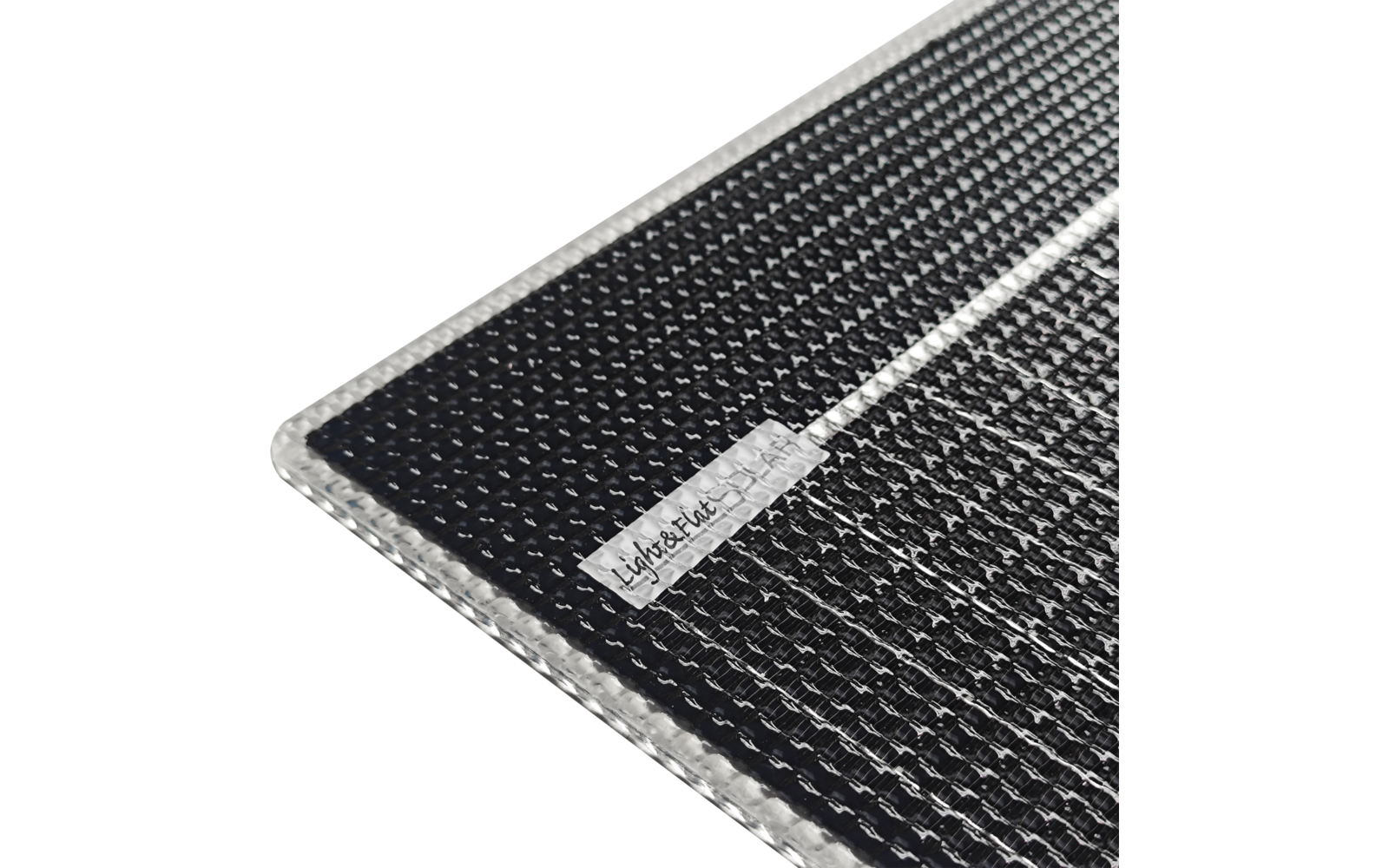 Gros plan d'un tapis noir texturé avec une bordure argentée et une étiquette blanche portant un texte foncé dans un coin