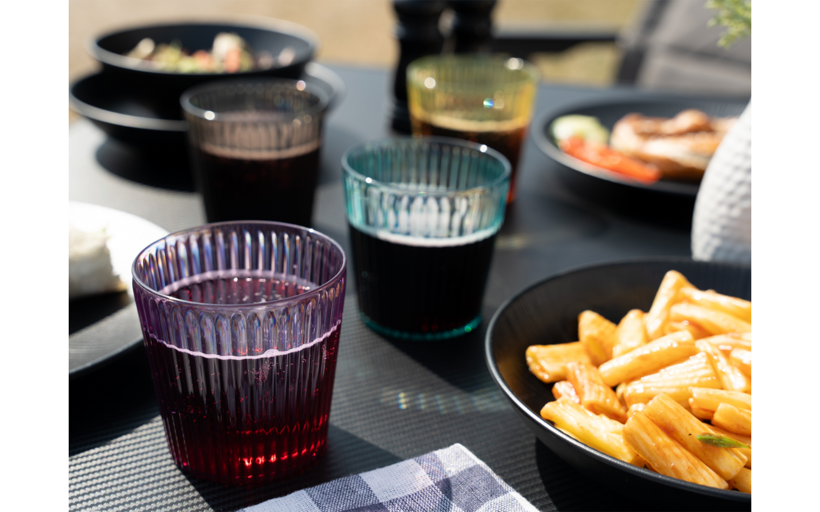Gläser mit Getränken, Teller mit Pommes und Sushi im Hintergrund