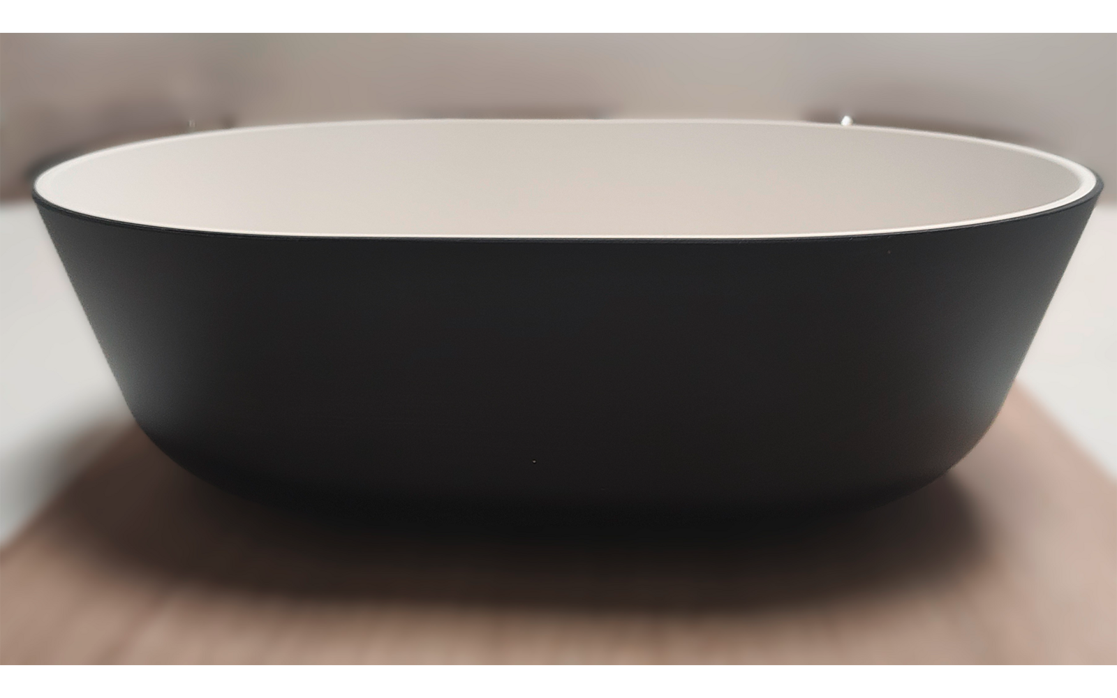 Black oval bowl with white interior on a wooden surface, blurred background