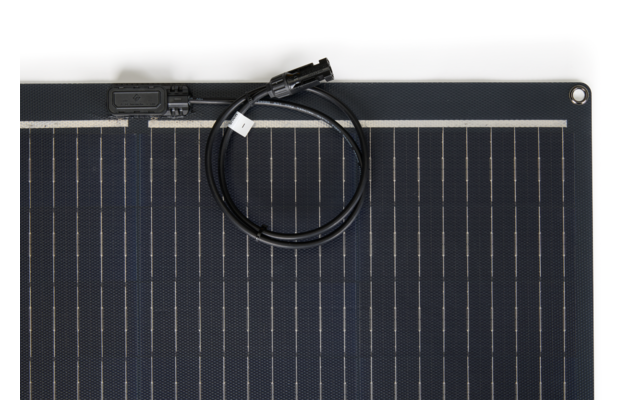 Top portion of a solar panel showing rectangular cells and a coiled black cable with connector on a white background