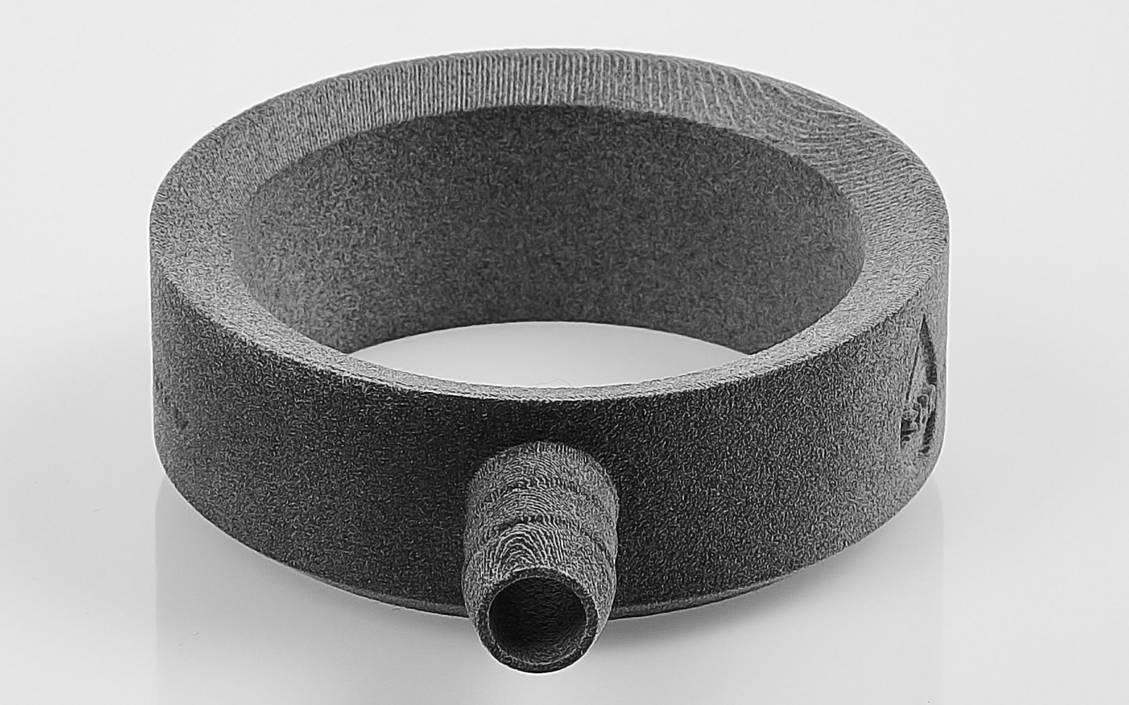 Anillo circular gris con una breve protuberancia cilíndrica en el lado exterior, sobre fondo blanco