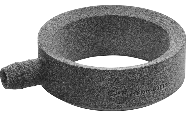 Anillo circular gris con una corta prolongación cilíndrica lateral y marca en relieve visible, sobre fondo blanco