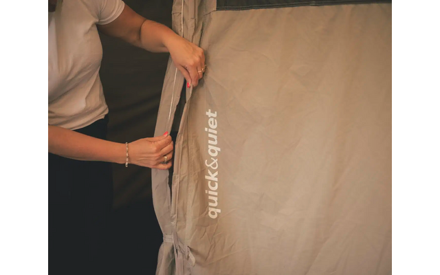 Person öffnet Reißverschluss an hellbraunem Zeltstoff mit Aufdruck quick&quiet