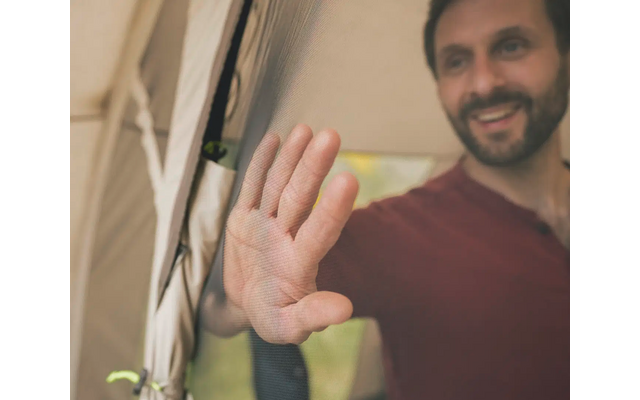 Mann lächelt hinter einem Netz, Hand leicht erhoben