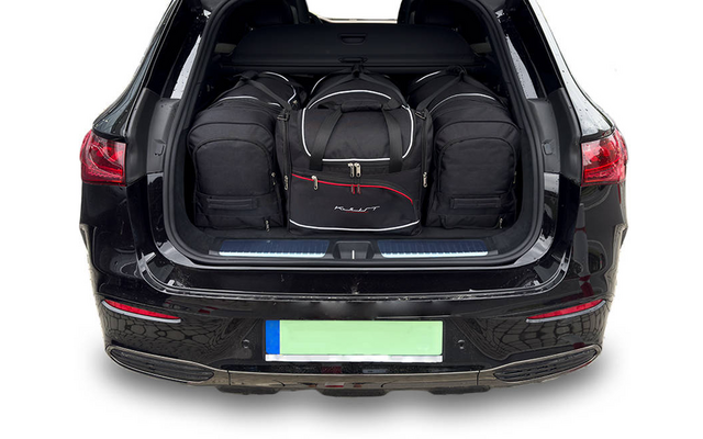 Coffre ouvert d'une voiture noire contenant plusieurs sacs de voyage et sacs à dos noirs