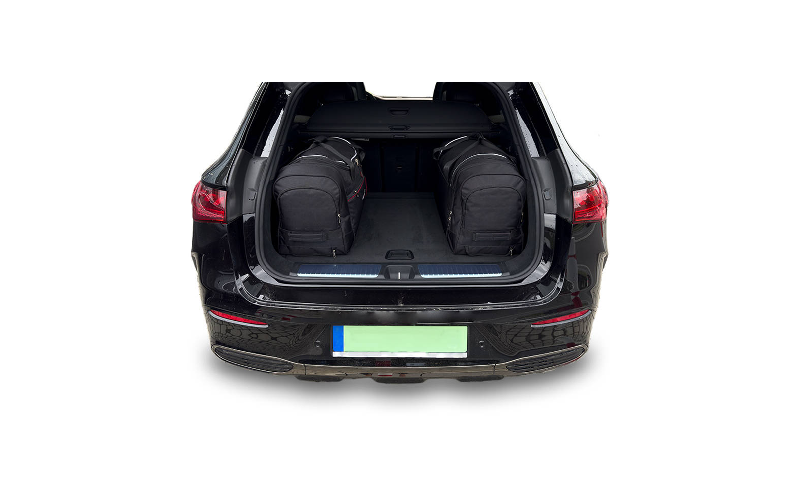 Coffre ouvert d'une voiture noire avec deux sacs de voyage noirs et une plaque d'immatriculation visible