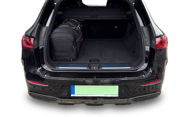Coffre ouvert d'une voiture noire avec un sac à dos noir à gauche dans l'espace de chargement