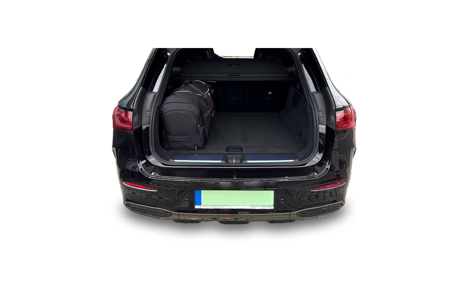 Coffre ouvert d'une voiture noire avec un sac à dos noir à gauche dans l'espace de chargement