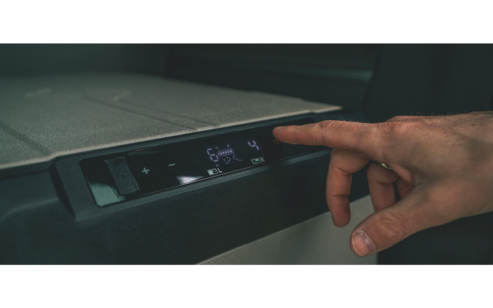 Rechte Hand berührt digitales Bedienfeld mit beleuchteten Symbolen und Zahlen