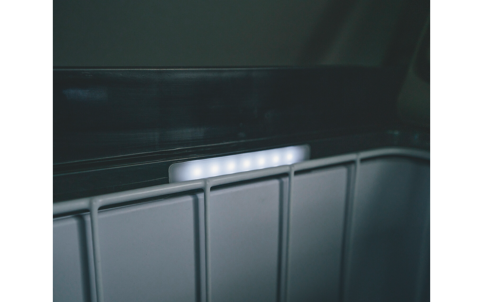 Weiße LED-Lichtleiste über hellgrauen vertikalen Kunststoffpanelen