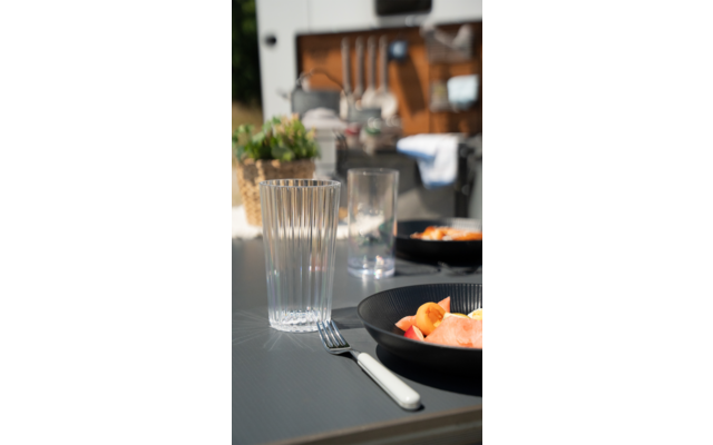 Ein Glas mit Wasser, Teller mit Essen und Besteck auf einem gedeckten Holztisch in einem Restaurant