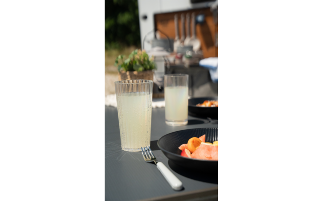 Tisch mit zwei Gläsern Limonade, schwarzen Tellern und Besteck im Freien