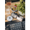 Holztisch mit Glas Wasser, Glas mit Getränk, Teller mit Oliven, Serviette mit Besteck und Pflanzen im Hintergrund