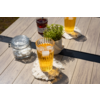 Zwei Gläser mit hellem Getränk und Eiswürfeln auf Makramee-Untersetzern auf einem Holztisch; daneben ein Glas mit Zuckerwürfeln, ein Glas mit dunklem Inhalt und eine kleine grüne Topfpflanze