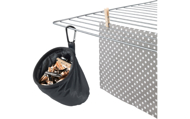Metallgittergestell; rechts ein graues Tuch mit weißen Punkten, mit einer Holz-Wäscheklammer an einer Stange befestigt; links ein schwarzer Stoffbeutel mit Holz- und Metallwäscheklammern, mit Karabinerhaken am Gestell befestigt