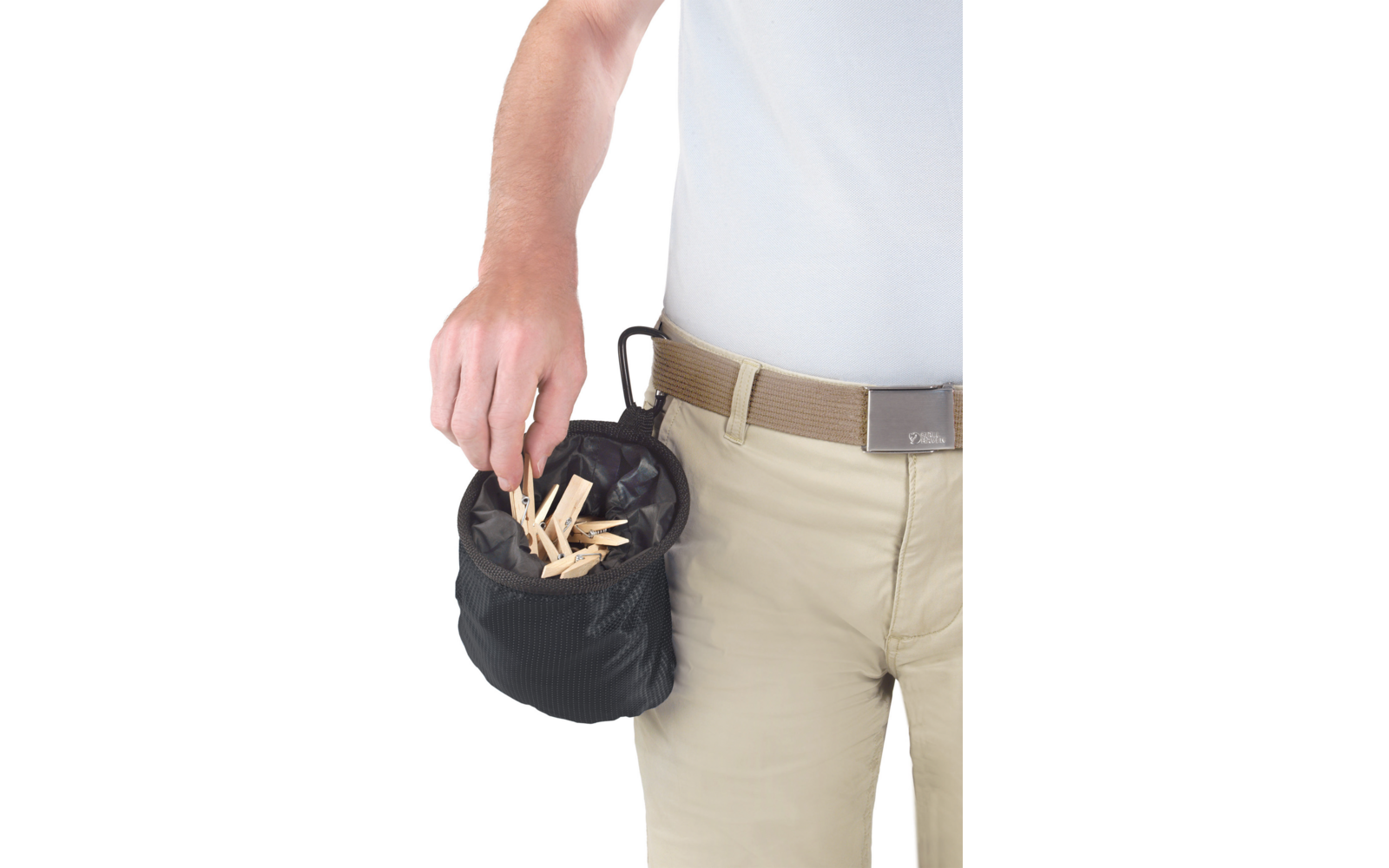 Oberkörper und Hüfte einer Person mit weißem T‑Shirt und beiger Hose samt Gürtel; kleine schwarze Stofftasche mit mehreren hölzernen Wäscheklammern, Hand hält eine Klammer