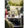 Table pliante avec une lanterne, un verre contenant des ustensiles de cuisine, un petit vase avec des fleurs séchées et une voiture verte en arrière-plan