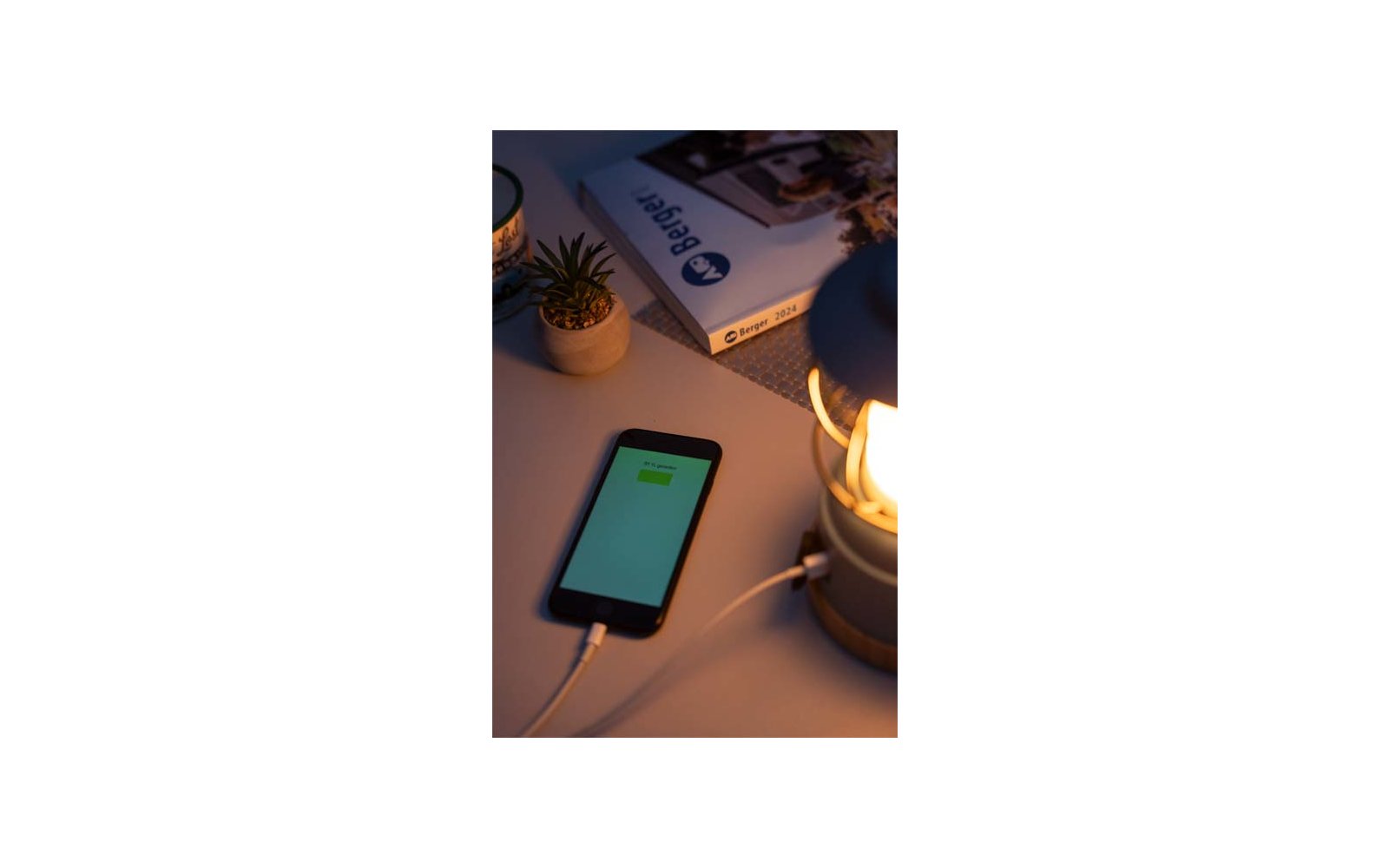 Smartphone met ingeschermd scherm naast een lamp en een kleine plant