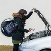 Person mit Winterjacke benutzt Diagnosegerät an offenem Motorraum eines Autos