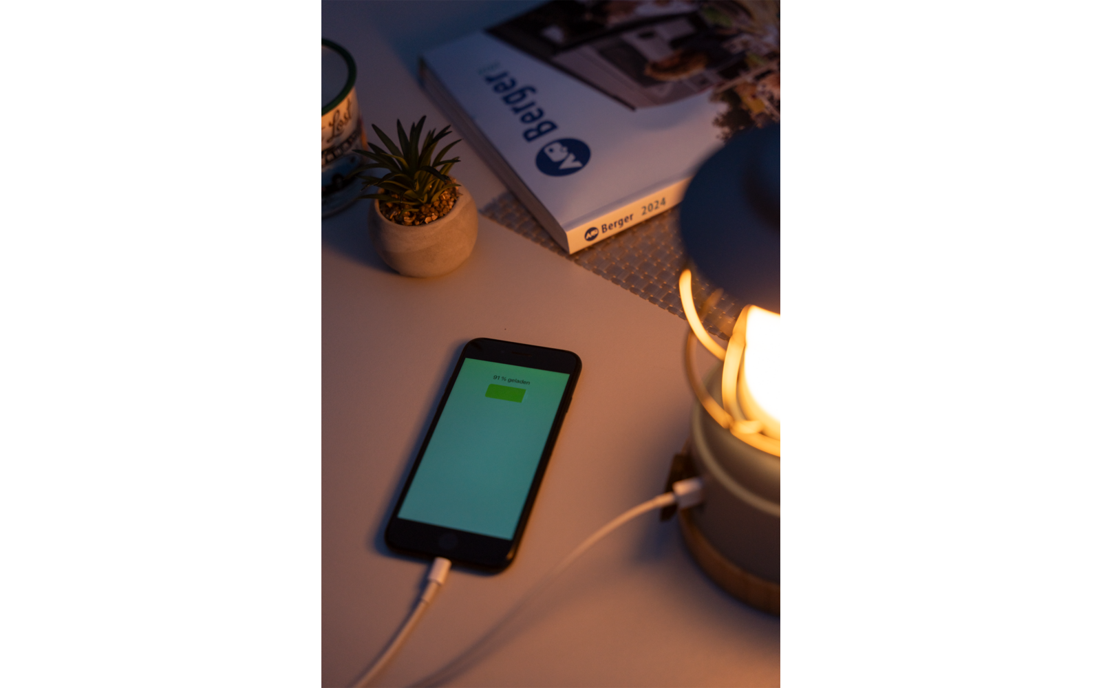 Smartphone avec écran allumé à côté d'une lampe et d'une petite plante