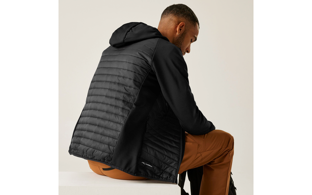 Mann sitzt seitlich, trägt eine schwarze Steppjacke und braune Hose